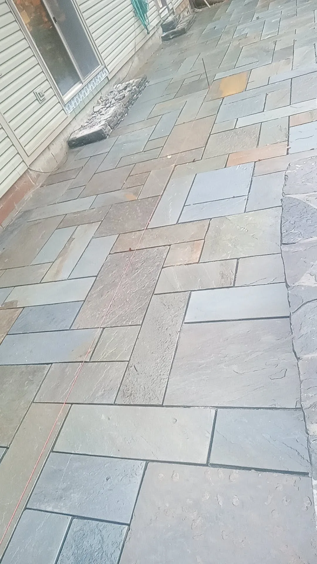 Wide bluestone patio taking shape behind a home
