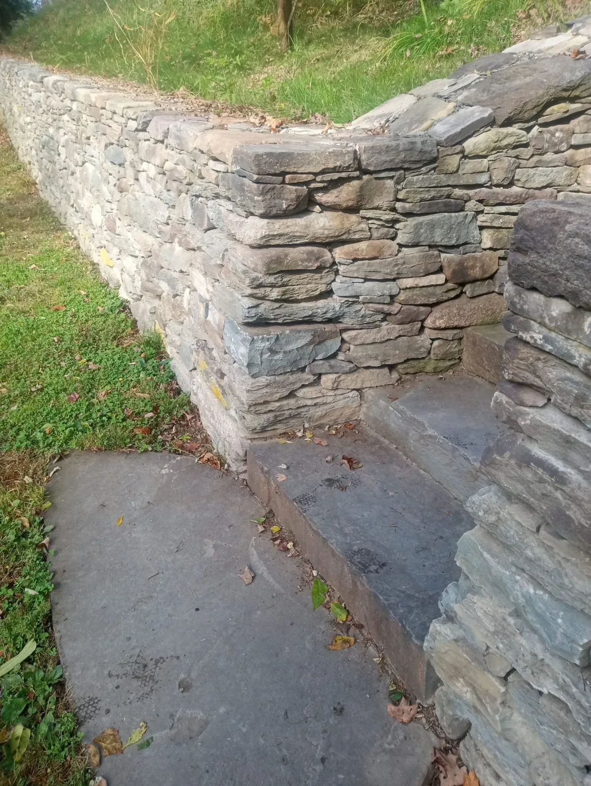 Dry-stacked stone retaining wall with slate steps